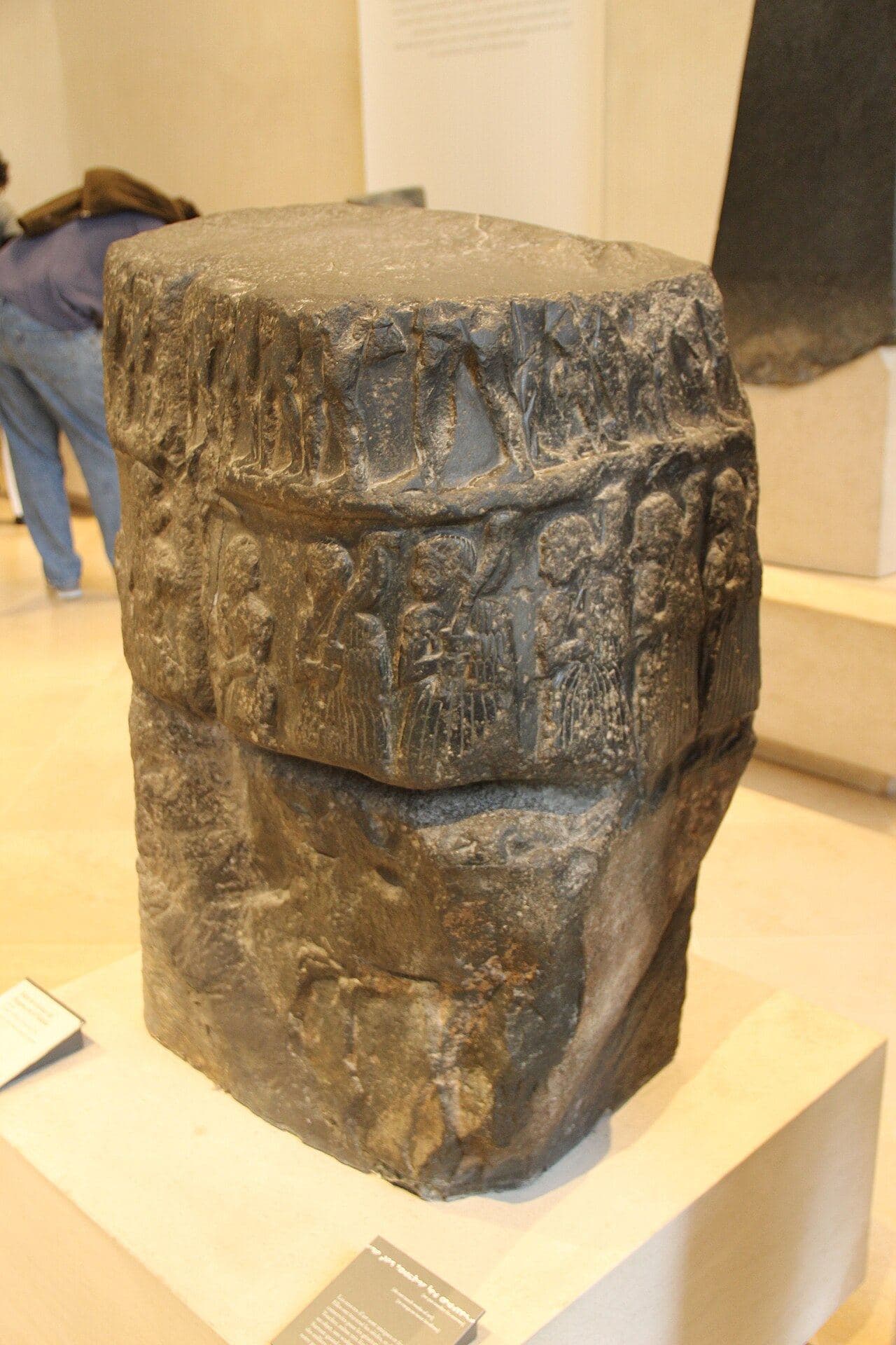 Battered fragment of a carved stone victory monument showing part of a ruler's figure